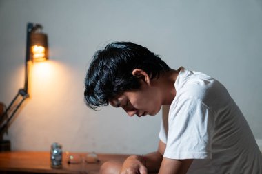 Kafası aşağıda oturan beyaz gömlekli bir insan derin düşüncelere ya da üzüntüye dalmış gibi görünüyor. Arka planda bir lamba ve bir çift gözlük ve küçük bir kavanoz ile ahşap bir yüzey yer alıyor..