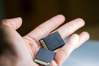 İki SD hafıza kartını tutan bir elin yakın plan görüntüsü. Arka plan bulanık, dikkatleri hafıza kartlarına odaklıyor..