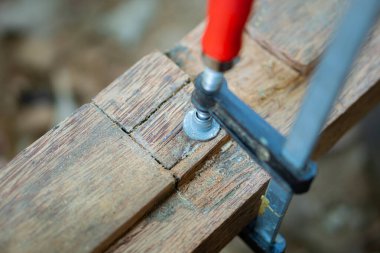 Tahta kıskacının yakın plan görüntüsü. İki parça tahtayı vidayla bir arada tutuyor..