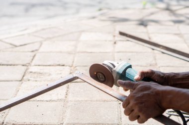 Dışarıdaki asfalt yüzeyde metal kesmek için açı öğütücü kullanan biri..