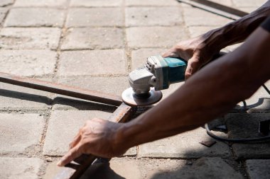 Dışarıdaki asfalt yüzeyde metal kesmek için açı öğütücü kullanan biri..