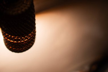 Örülmüş bir abajura yakın çekim ve arka planı aydınlatan sıcak bir ışık..