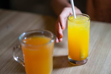 Bir bardak portakal suyu, bir pipet ve bir kupa portakal suyu..