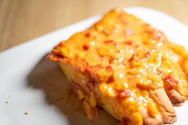 Beyaz tabakta bir dilim peynirli pizza ekmeğinin yakın çekimi. Ekmek eritilmiş peynir ve küçük pepperoni parçalarıyla kaplıdır..