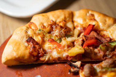 Tahta bir yüzey üzerinde dolmalık biber, mantar ve ananas içeren çeşitli malzemelerle yakın plan pizza..