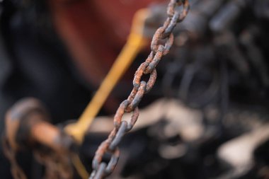 Paslı bir zincire yakın çekim, arka planı bulanık, metalin dokusunu ve çürümesini vurguluyor..