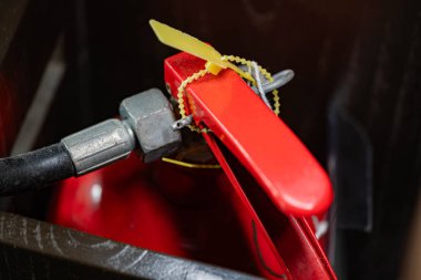 Sarı güvenlik kilidi olan kırmızı bir yangın söndürücünün yakın çekimi..