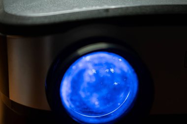 Bulanık arkaplan ile mavi ışık yayan projektör lensinin yakın plan görüntüsü.