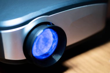 Ahşap bir yüzeye yerleştirilmiş mavi renkli modern projektör lensi..