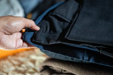 Koyu renk kıyafetlere odaklanarak katlanmış giysileri sınıflandıran bir insan..