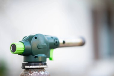 Lehim, ısıtma ve pişirme gibi çeşitli uygulamalarda kullanılan yeşil düğmeli bir gaz üfleme meşalesinin yakın çekimi..