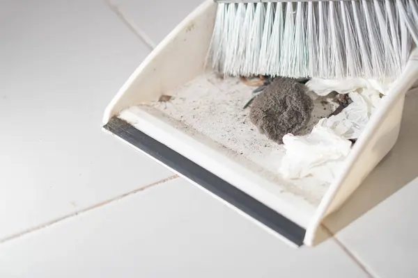 Döşeme üzerinde toz, toprak ve buruşuk mendillerle dolu bir süpürgeyle faraş..