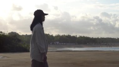 Plajda siyah elbiseli genç bir kadının silueti.