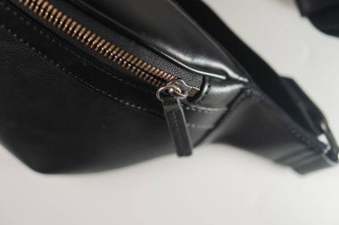 Pürüzsüz tasarımı ve yüksek kaliteli malzemeleriyle fermuarlı, şık siyah deri bir çantanın yakın plan görüntüsü..