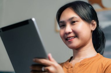 Şaşırmış bir kadın büyük gözleri ve göğsünde bir eliyle tablete bakıyor, şaşkınlık ya da heyecan ifade ediyor. Arkaplan özellikleri bulanık dijital ekranlar.