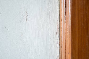 Açık mavi bir duvarın yakın plan görüntüsü ahşap bir çerçeveyle buluşması düz duvar yüzeyi ve doğal ahşap tahıl arasındaki kontrastı gösteriyor..