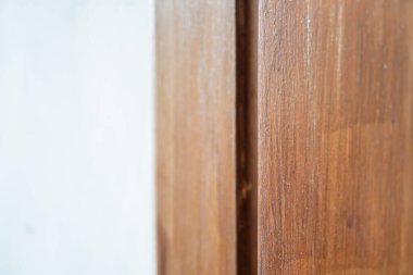 Açık mavi bir duvarın yakın plan görüntüsü ahşap bir çerçeveyle buluşması düz duvar yüzeyi ve doğal ahşap tahıl arasındaki kontrastı gösteriyor..