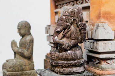 Hindu fil başlı tanrı Ganesha 'nın taş heykeli ön planda belirgin bir şekilde sergilenmektedir. Arkasında, meditasyon yapan bir keşişin heybetli taş figürü kısmen görülebiliyor.