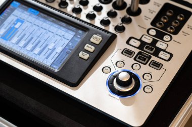 Çeşitli düğmeler, düğmeler ve dijital ekran içeren modern bir ses karıştırma konsolunun yakın görüntüsü. Konsol profesyonel ses karıştırma ve kaydetme için tasarlandı, sezgisel bir gösterim için.