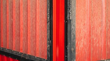 Kalıplı yüzeyi ve siyah çerçevesi olan kırmızı metal bir depolama konteynırının yakın çekimi. Görüntü, iki panelin buluştuğu köşeyi yakalar, aşınır ve yıpranır.
