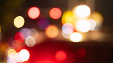 Değişik şekil ve boyutlarda renkli bokeh ışıklarının yer aldığı bulanık bir gece sahnesi canlı ve soyut bir atmosfer yaratıyor. Işıklar araçlardan geliyor gibi görünüyor.