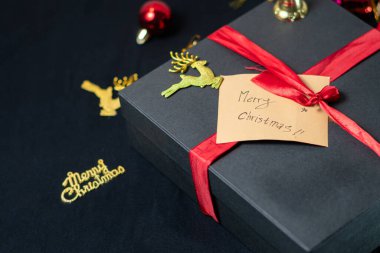 Kırmızı kurdele ve altın rengeyiği süslemesi ile süslenmiş güzel bir siyah hediye kutusu. Kurdeleye iliştirilmiş etikette 
