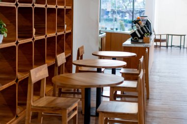 İçinde ahşap masalar ve sandalyeler olan rahat bir kafe. Mekanın arka planında ahşap bir raf ünitesi olan minimalist bir tasarımı var. Doğal ışık filtreleri la 'dan geçer