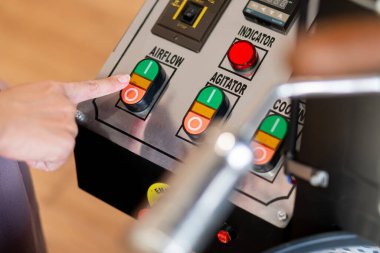 Üzerinde hava akışı, kışkırtıcı ve soğutucu etiketli düğmeler olan bir kontrol panelinin yakın çekimi. Bir parmak hava akışı düğmesine basıyor. Panelde çeşitli göstergeler var.