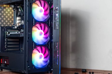 Üç RGB soğutma fanatiğinin yer aldığı modern bir bilgisayar dosyasının yakından görüntüsü. Hayranlar canlı bir renk yelpazesi göstererek görsel olarak çekici bir etki yaratıyorlar. Çanta.