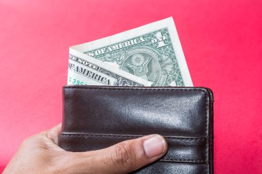 Bir dolarlık banknot kısmen koyu kahverengi deri bir cüzdana yapışmış..
