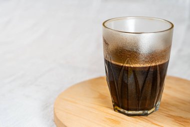 Tahta bir yüzeye köpüklü kremalı bir bardak sade kahve..