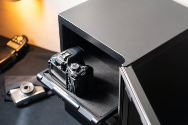 Yakınlardaki diğer kameralarla birlikte siyah bir elektronik kasada depolanmış bir SLR kamera..