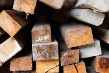 Ahşap istiflenmiş tahtaların yakın plan görüntüsü, ahşabın çeşitli dokularını ve renklerini sergiliyor. Düzenleme, kerestenin doğal tahılı ve kusurlarını vurguluyor..