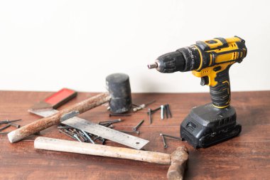 Kablosuz matkap, çekiç, cetvel ve tahtadan bir yüzeye saçılmış vidalar YID projeleri için çeşitli araçlar sergiliyor..