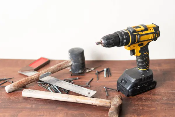 Kablosuz matkap, çekiç, cetvel ve tahtadan bir yüzeye saçılmış vidalar YID projeleri için çeşitli araçlar sergiliyor..