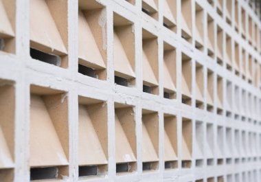 Çağdaş bir mimari tasarım sergileyen, üçgen kesimli beton bloklardan yapılmış, desenli bir duvarın yakın plan görüntüsü..