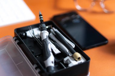 Akıllı bir telefon ve klavyenin yanındaki masaya yerleştirilmiş çeşitli tornavida ve araçları içeren bir araç takımının yakın plan görüntüsü.