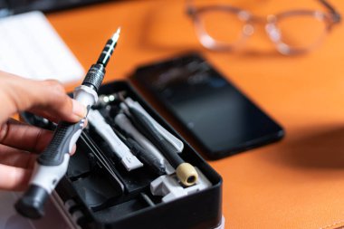 Akıllı bir telefon ve klavyenin yanındaki masaya yerleştirilmiş çeşitli tornavida ve araçları içeren bir araç takımının yakın plan görüntüsü.