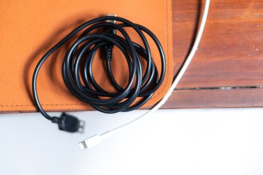 Siyah bir SUB kablosunun yakın çekimi ahşap bir masada dinleniyor, bir çift gözlük ve arka planda bir defter, rahat bir çalışma alanı atmosferi yaratıyor..