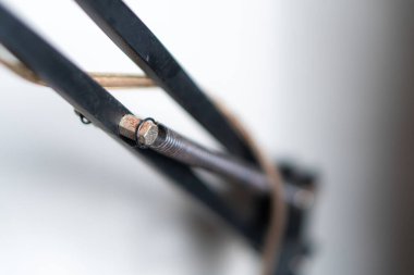 Üzerinde desenli silindirik bir nesnenin asılı olduğu mekanik bir kolun yakın çekim görüntüsü. Kol, endüstriyel tasarım ve işlevselliğin bir karışımını gösteren metalik bir cıvata ve yay içeriyor..