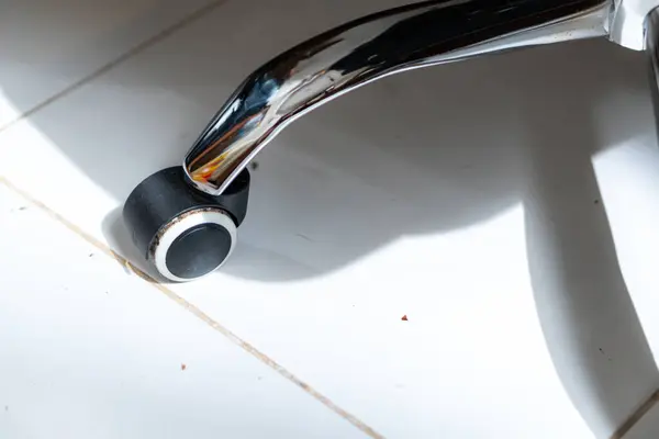 Kiremitlerle döşenmiş bir yerde siyah ve gümüş bir ofis sandalyesine yakın plan, güneş ışığı gölgeleri yansıtıyor..