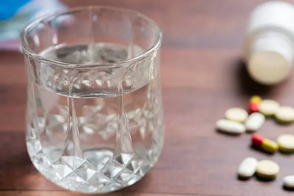 Dağılmış haplarla dolu ahşap bir masa, şırınga, ve açık bir hap şişesi, tıbbi ya da ilaç temalı.