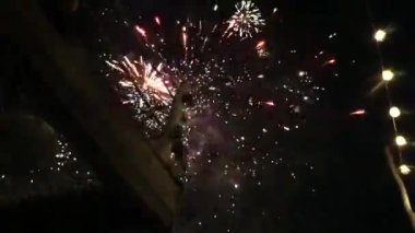 Yeni yılın havai fişekleri, balkonun altında çekim, Gece Vakti Şenlikli Işıklarla Patlayan Havai fişekler