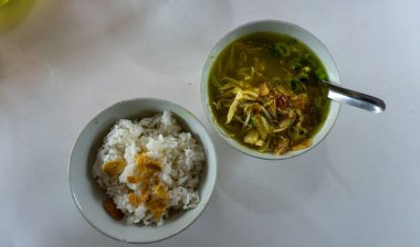 Bir kase pirinç ve beyaz masa üzerinde tavuk çorbası.