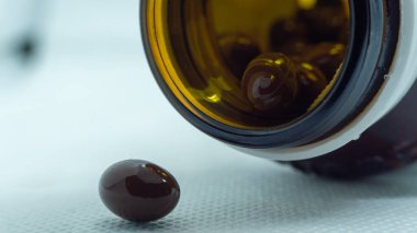 Kapsüllerin Yakın Çekimi ve Beyaz Yüzeyde Açık İlaç Şişesi