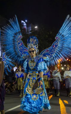 Yogyakar, Endonezya-6 Ağustos 2025: Canlı ışıklar altında neşe ve kutlama saçan, karmaşık tasarımlar ve kanatlarla süslenmiş çarpıcı mavi bir kostümün katılımcısını gösteren karnaval etkinliği. Kültürel şenliğin canlı bir atmosferi.