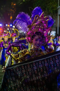 Yogyakarta, Endonezya-6 Ağustos 2025: Canlı geleneksel kostümler giymiş katılımcıların sergilendiği festival gecesi geçit töreni. Sahne renkli ışıklarla aydınlatılıyor ve dans yoluyla kültürel mirasa ve kutlamaya odaklanıyor. 