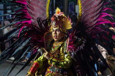 Yogyakarta, Endonezya-6 Ağustos 2025: Hareketli bir sanatçı, coşkulu bir kutlamayla aydınlık kültür sanatını gözler önüne seren, siyah ve pembe kanatların yer aldığı, karmaşık detayların yer aldığı özenle hazırlanmış bir kıyafetle seyirciyi büyülüyor 