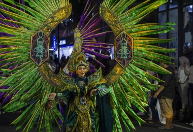 Yogyakarta, Endonezya-6 Ağustos 2025: Karmaşık desenli renkli festival kostümü, canlı yeşil ve sarı renkler bir gece kültür geçit töreninde kalabalığı büyülüyor. Ayrıntılı detaylar ve şenlik ruhu coşkulu kutlamaya hakim. 