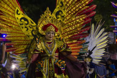 Yogyakarta, Endonezya-6 Ağustos 2025: Renkli festival kutlaması, açık havada geleneksel kültür ve sanatsal ifadeyi temsil eden, parlak altın renkli bir kostüm ve kanatlarla bir sanatçıyı sergiliyor.
